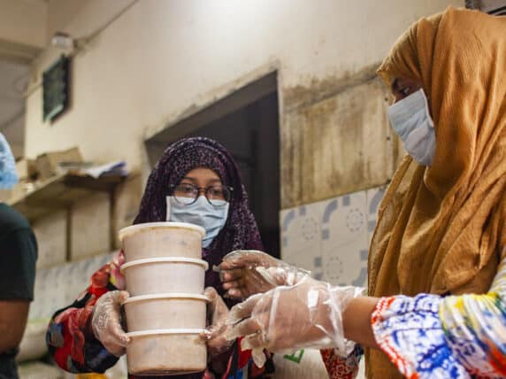 Volunteers at Bidyanando Foundation distributing cooked food in boxes to give to the marginalized people affected the most during the coronavirus pandemic.