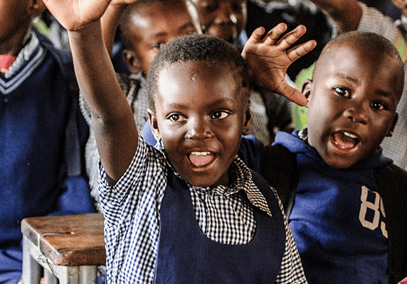 Children in school in Zambia raising their hands