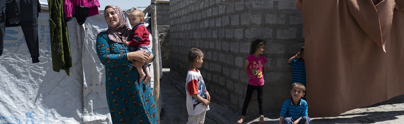 A Syrian-Kurdish woman and several children stand outside a home in Darashakran refugee camp in Iraqi Kurdistan