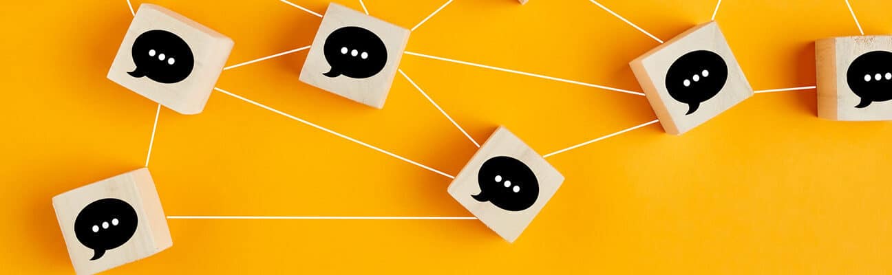 Concept of online communication or social networking. Wooden cubes with speech bubbles linked to each other.