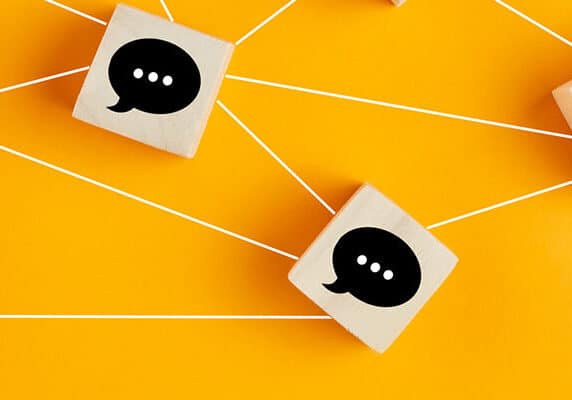 Concept of online communication or social networking. Wooden cubes with speech bubbles linked to each other.