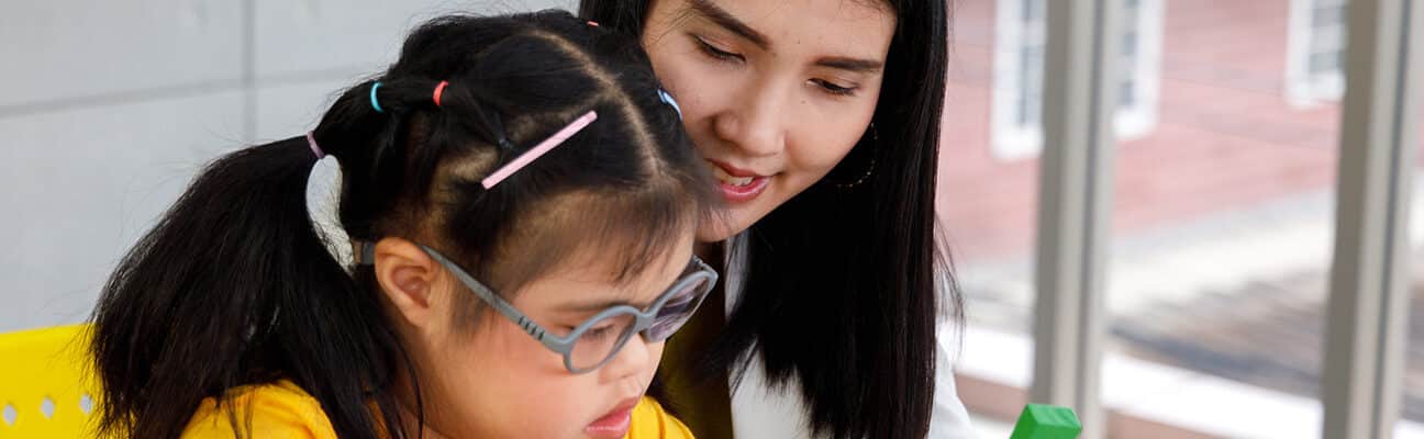 girl with Down's syndrome play puzzle toy with her teacher.