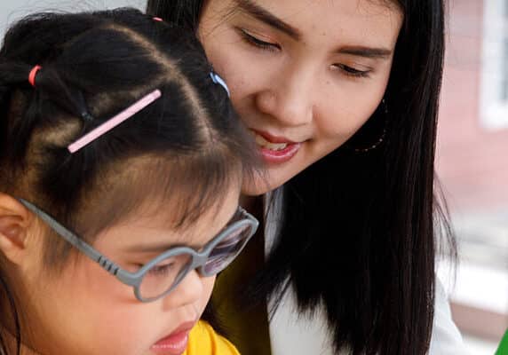 girl with Down's syndrome play puzzle toy with her teacher.