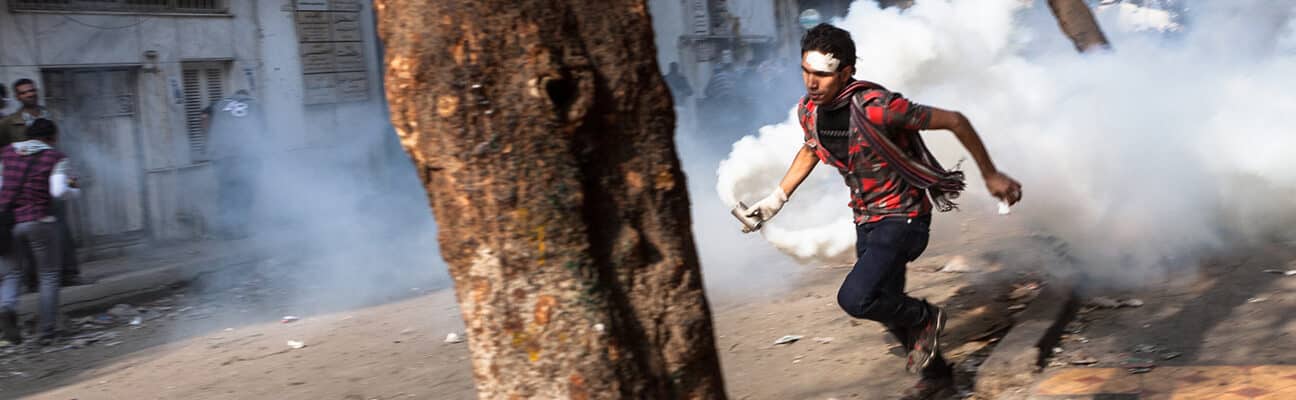 "Cairo, Egypt - November 23, 2011: A young man near Tahrir Square is running with a container of riot gas that the police just fired at the protestors.