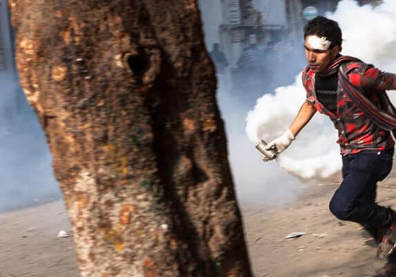 "Cairo, Egypt - November 23, 2011: A young man near Tahrir Square is running with a container of riot gas that the police just fired at the protestors.