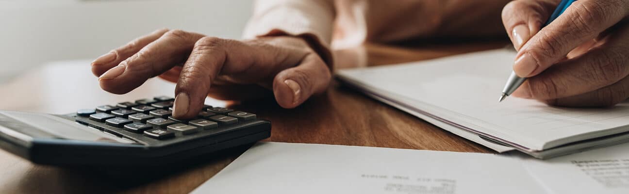 Close up of woman planning home budget and using calculator.