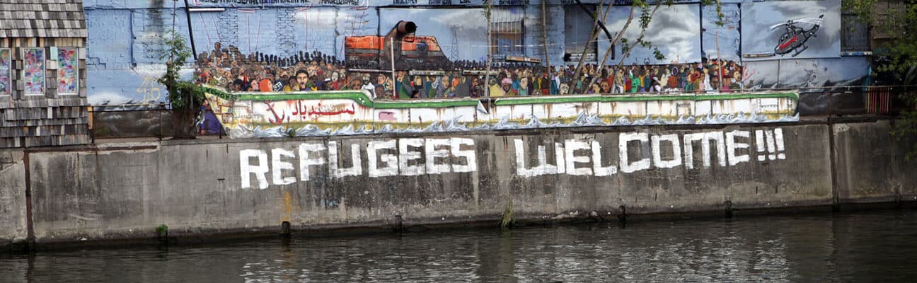 Riverside designed as a boat and Refugees Welcome written on wall