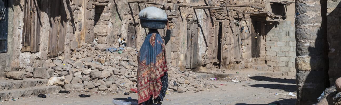 Woman walking through ruined area of Sana'a, Yemen