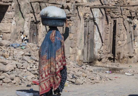 Woman walking through ruined area of Sana'a, Yemen