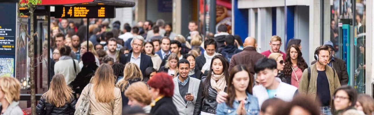 Crowded pavement on Oxford Street with commuters and tourists.