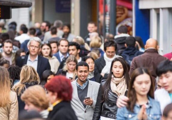 Crowded pavement on Oxford Street with commuters and tourists.