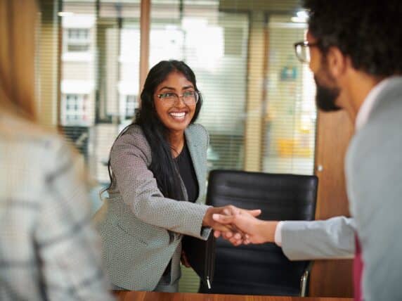 Young female graduate smiling and shaking hands with male