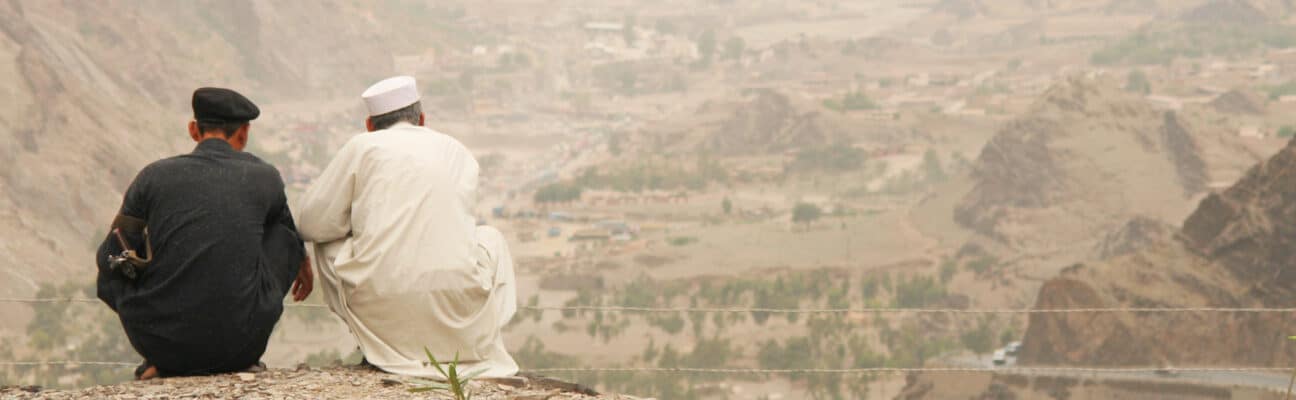 Two Pakistani men looking over the mountains at the Pakistan-Afghanistan border. The mountain in the background are in Afghanistan. Credit: philmcelhinney