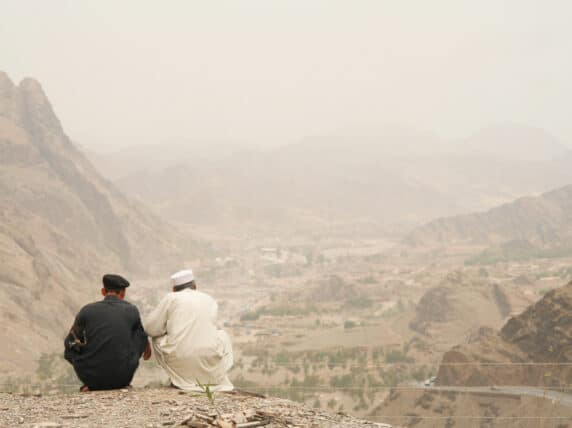 Two Pakistani men looking over the mountains at the Pakistan-Afghanistan border. The mountain in the background are in Afghanistan