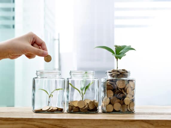Woman putting a coin in jars with plants. Credit: baona