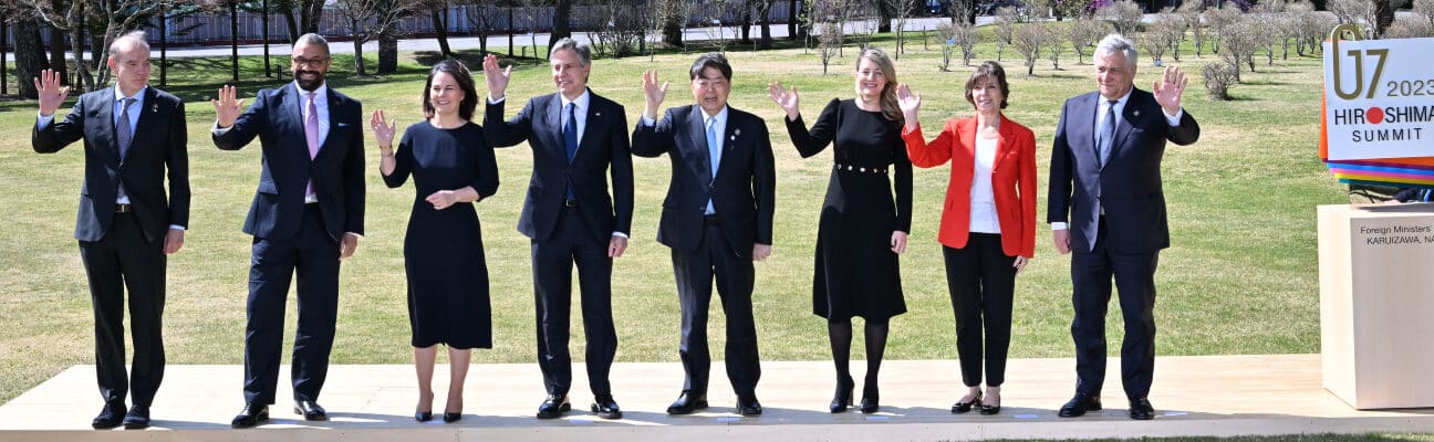 G7 leaders standing and waving against backdrop of trees and mountains Hiroshima