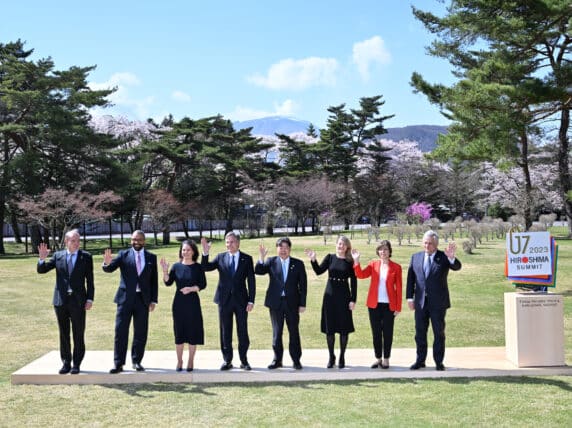 G7 leaders standing and waving against backdrop of trees and mountains Hiroshima