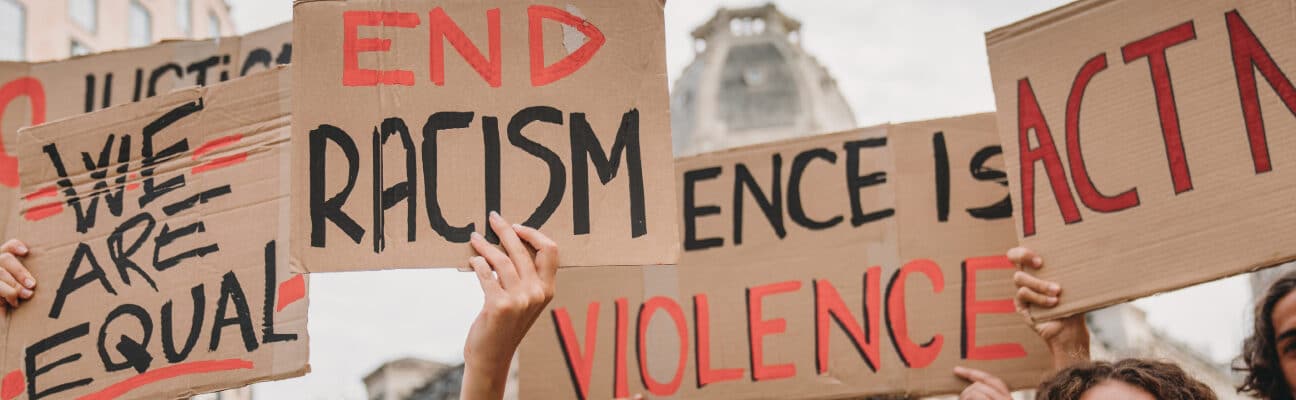 People are marching on strike against racism in the city. They are holding cardboard signs