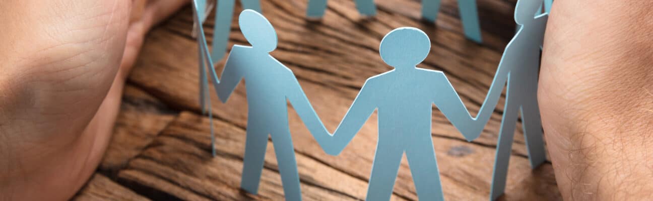 Cropped image of hands covering paper team on wooden table