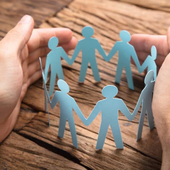 Cropped image of hands covering paper team on wooden table