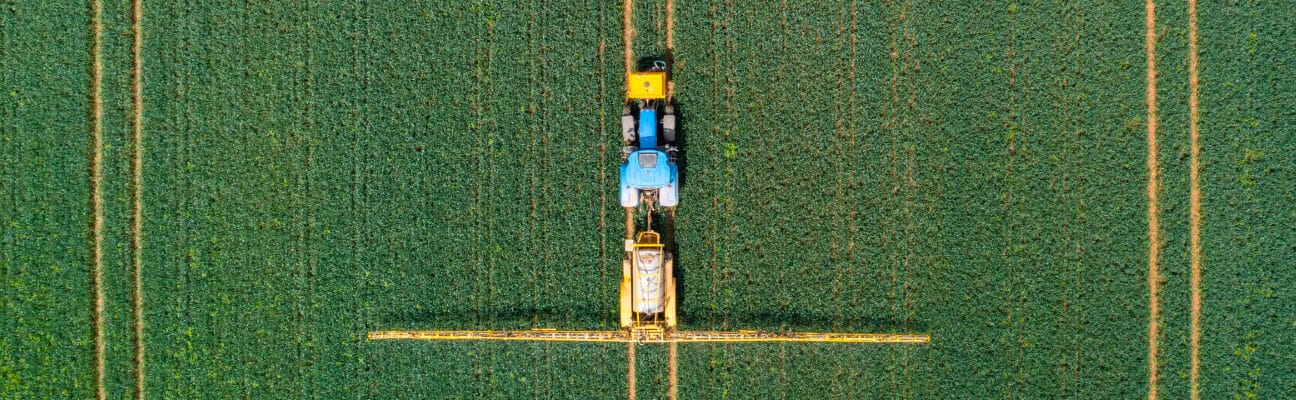 Aerial view of farming tractor crop sprayer in the countryside