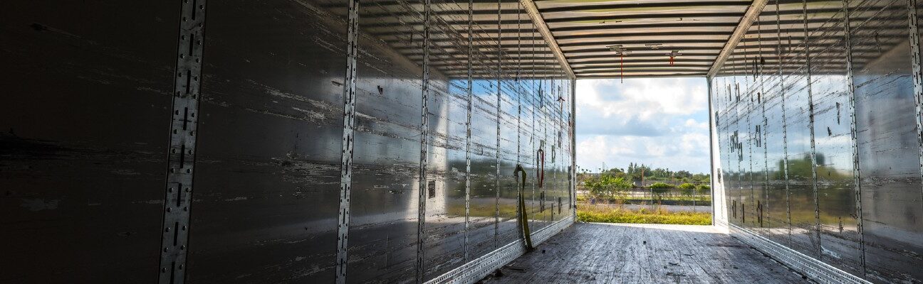 View of the inside of the rear of a huge empty freight truck with the rear doors open. Conceptual image about global human trafficking.