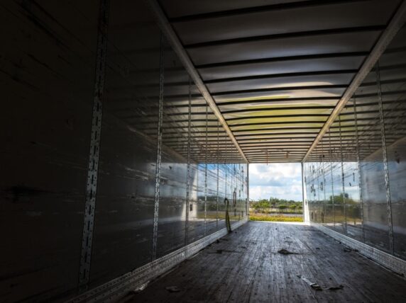 View of the inside of the rear of a huge empty freight truck with the rear doors open. Conceptual image about global human trafficking.