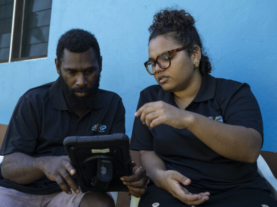 MEAL Coordinator Chloe Molou and Area Council Climate Change Officer Howard, 39, looking at a tablet in Torba Province. Credit: Save the Children
