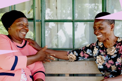 Two people seated on a bench outside a building reach toward each other while talking. Credit: Right to Childhood