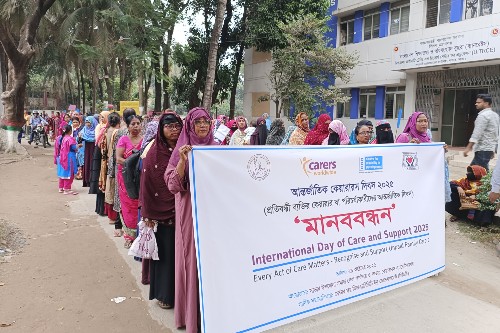 A large group of people taking part in a rally in Bangladesh, led by participants holding a banner marking International Day of Care and Support 2025. Credit: Carers Worldwide